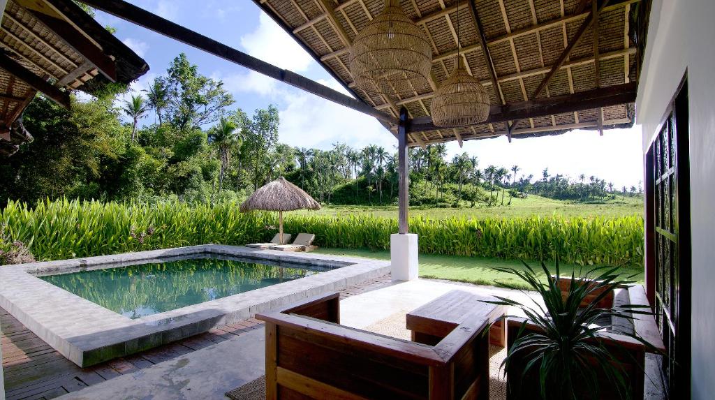 a patio with a pool and a table and chairs at Secret Villa - Unique Experience in General Luna