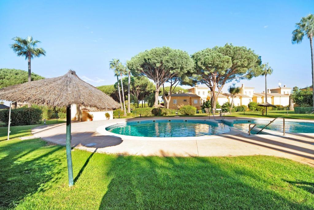 a swimming pool with an umbrella in a yard at Chalet Cormoran in Chiclana de la Frontera