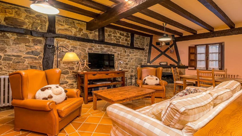 una sala de estar con sofás y una pared de piedra. en Casa rural con encanto en Potes by Alterhome, en Potes