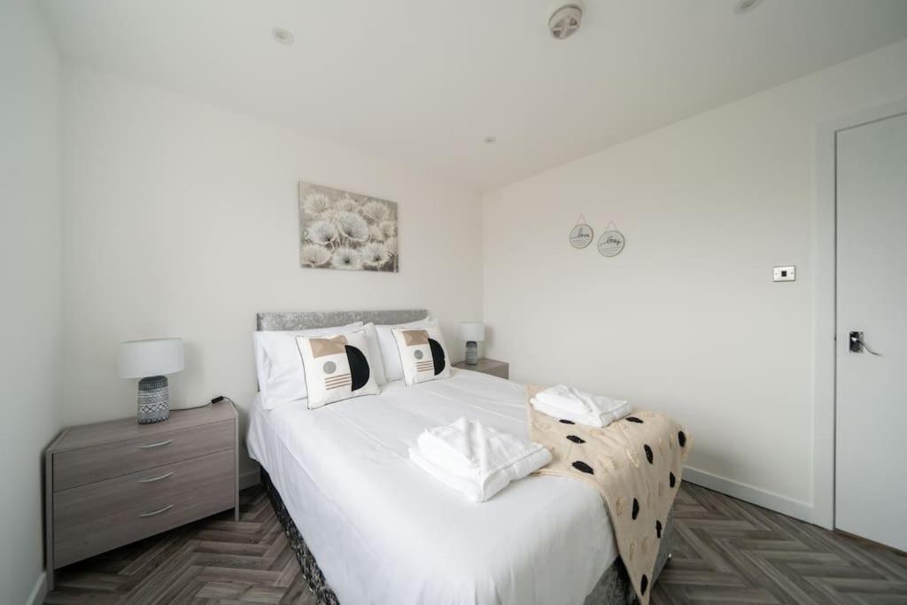 a white bedroom with a bed and a night stand at Links Loft -2 bed apartment minutes from Aberdeen beach in Aberdeen