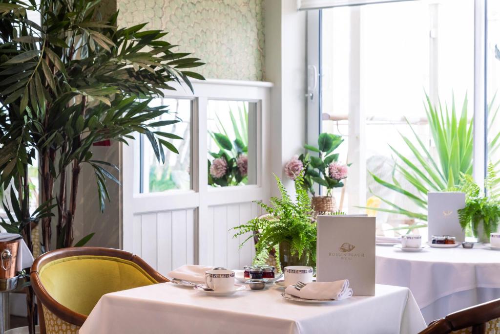 a restaurant with two tables and chairs and plants at Roslin Beach Hotel in Southend-on-Sea