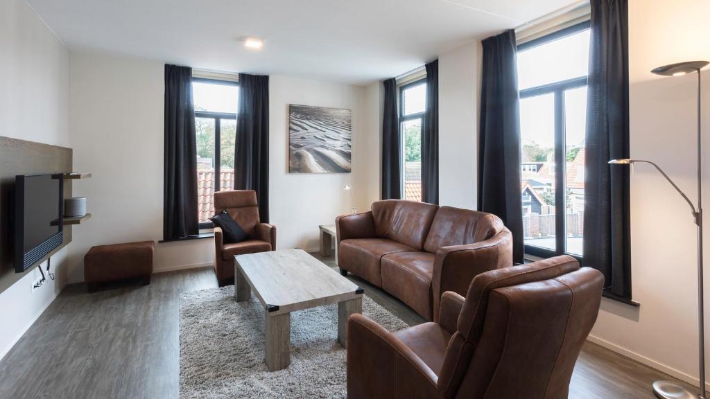 a living room with leather furniture and windows at Hello Zeeland - Appartement Wijngaerde Residence 19 in Domburg