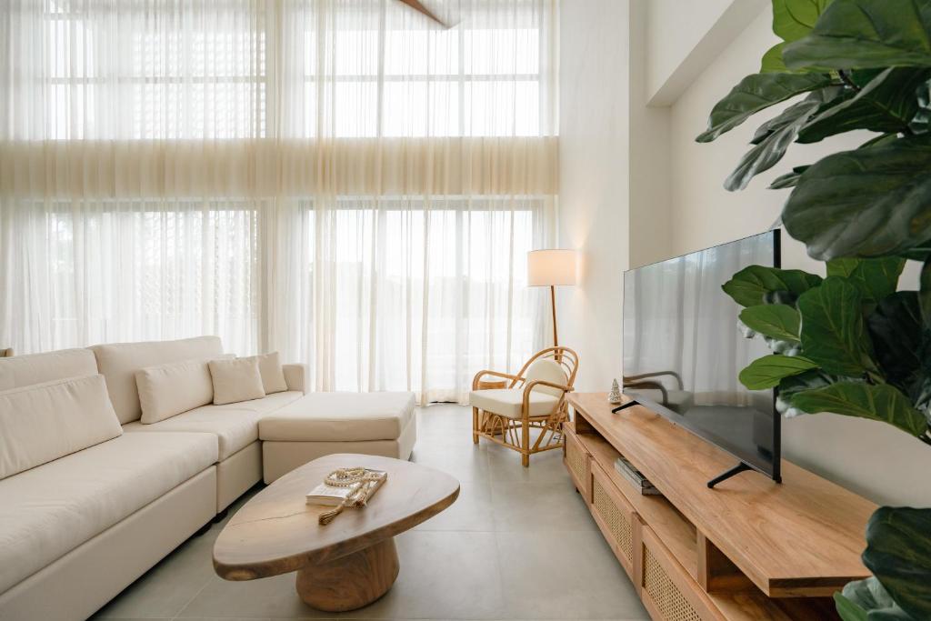 a living room with a white couch and a tv at Lumina at Flats Punta Cana Village in Punta Cana