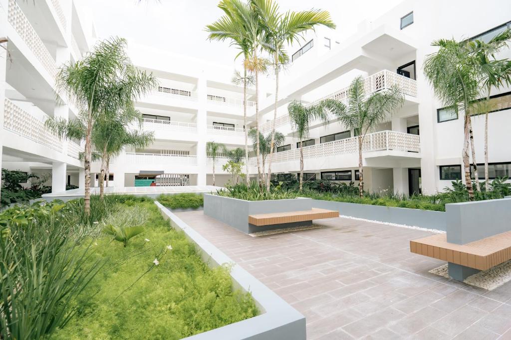 an apartment building with a courtyard with palm trees at Lumina at Flats Punta Cana Village in Punta Cana