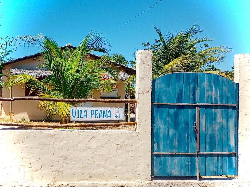 a blue gate in front of a building with palm trees at Vila Prana in Barra Grande
