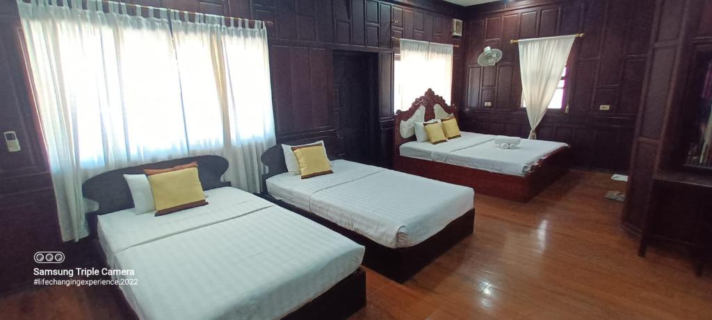 two beds in a room with wooden walls and wood floors at Mano boutique sun shine in Luang Prabang