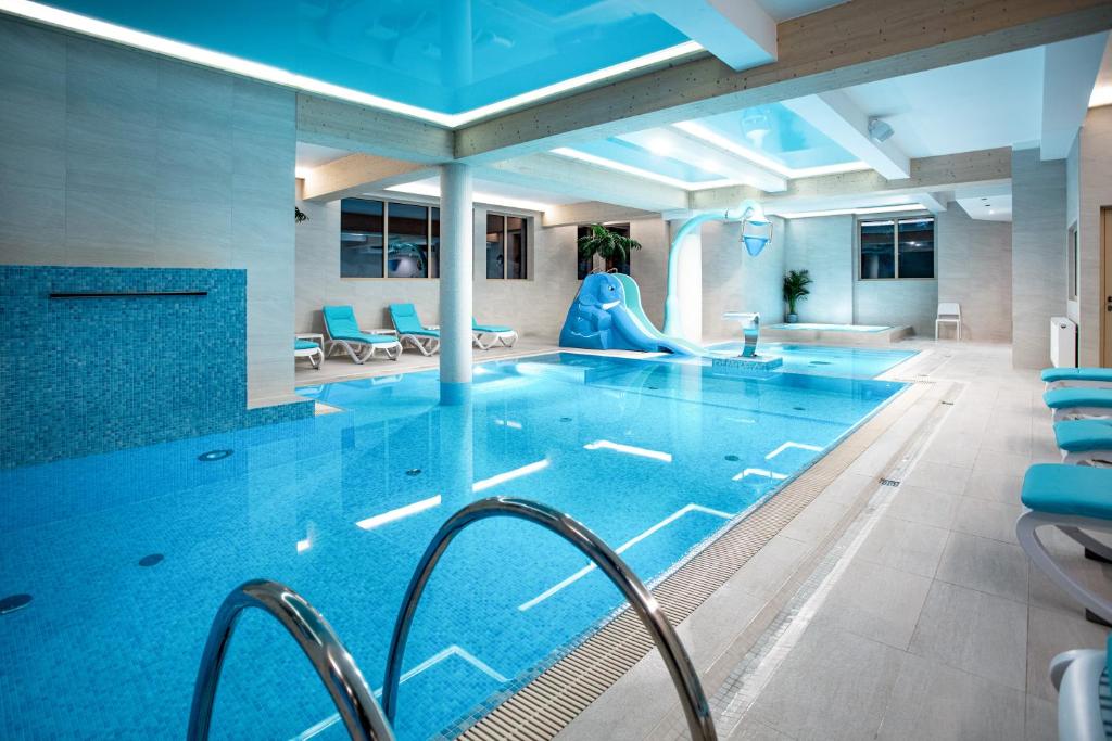 a swimming pool with a slide in a building at Villa Cannes Resort Zakopane - grota solna, sauna fińska in Zakopane