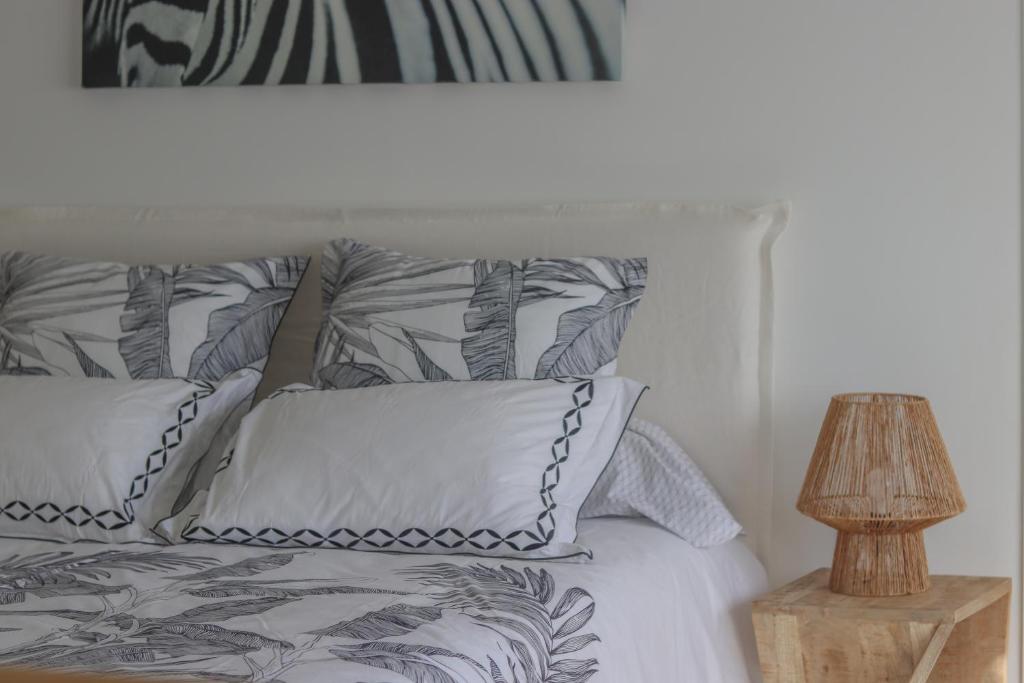a bed with gray and white pillows and a lamp at Chambre d'hôtes A Vadina Porticcio in Porticcio