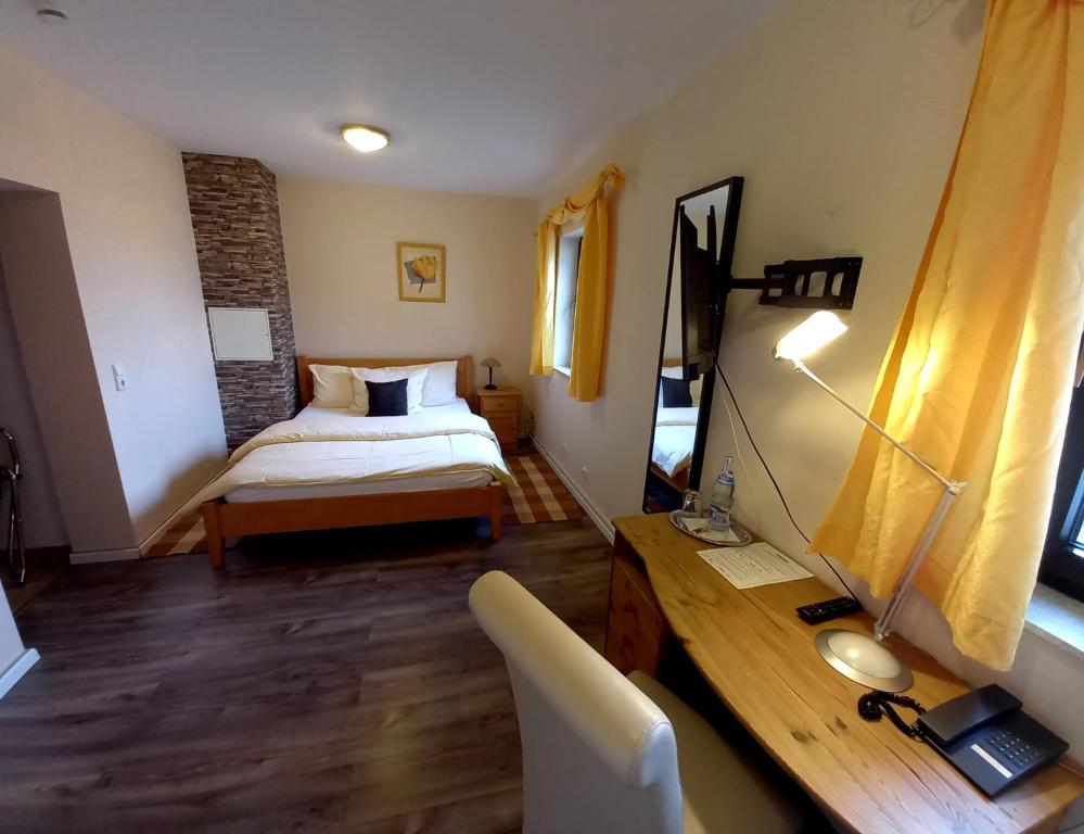 a bedroom with a bed and a desk in a room at Hotel Lindenhof in Rödermark