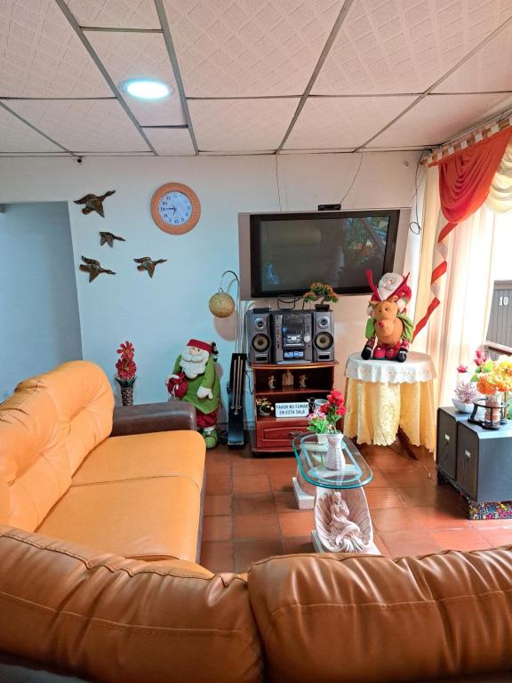a living room with a couch and a flat screen tv at Hotel Mi Casita Pereira in Pereira