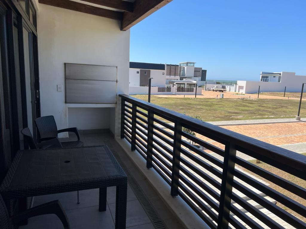 a balcony with a table and a view of a field at Kabeljauws Beach Estate in Jeffreys Bay