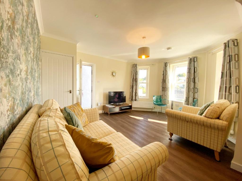 a living room with a couch and two chairs at Ockendon House Apartments in Torquay