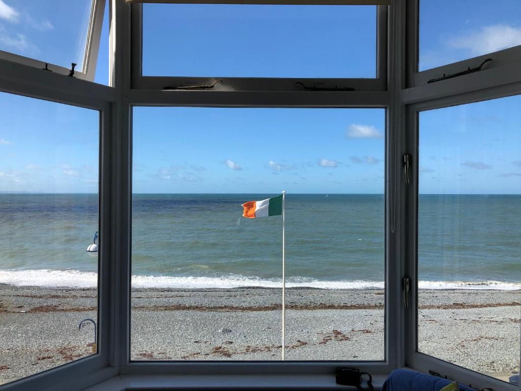 a window view of a beach with a flag at Stunning Aberystwyth South Beach Apartment in Aberystwyth