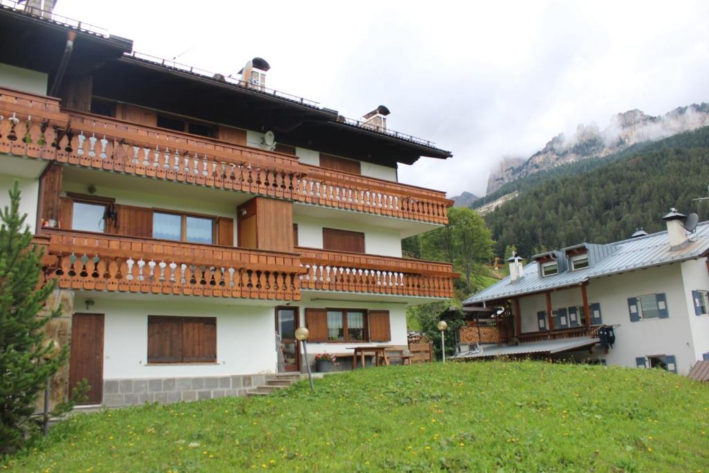 a building on a hill with mountains in the background at Cesa te Val in Vigo di Fassa