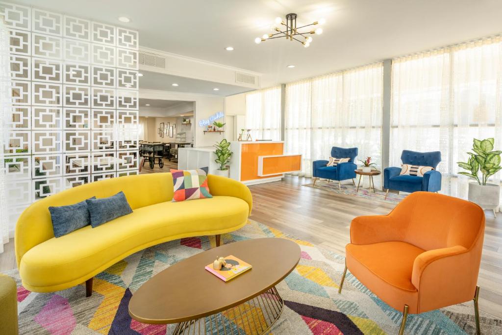 a living room with a yellow couch and two orange chairs at The Sojourn Los Angeles - Sherman Oaks in Sherman Oaks