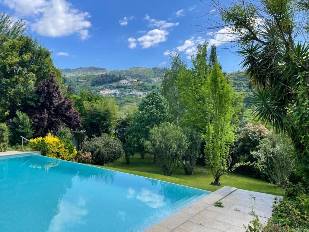 einen Pool in einem Garten mit Bäumen in der Unterkunft 5 bedrooms house with lake view shared pool and enclosed garden at Santa Cruz do Douro 1 km away from the beacha in Santa Cruz do Douro