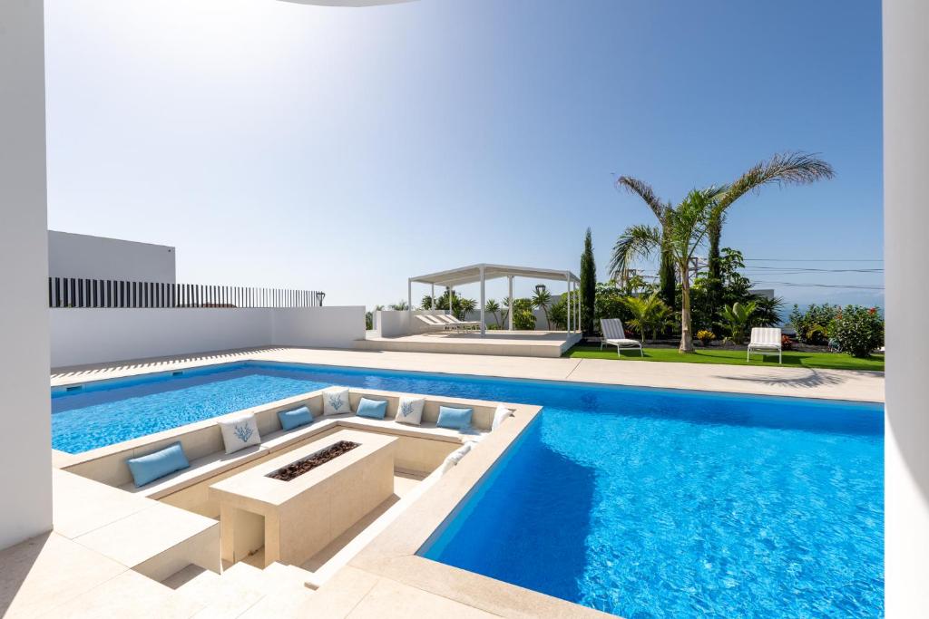 uma piscina com água azul numa casa em Villa Andrea, quiet luxury, sunset with sea views em Adeje