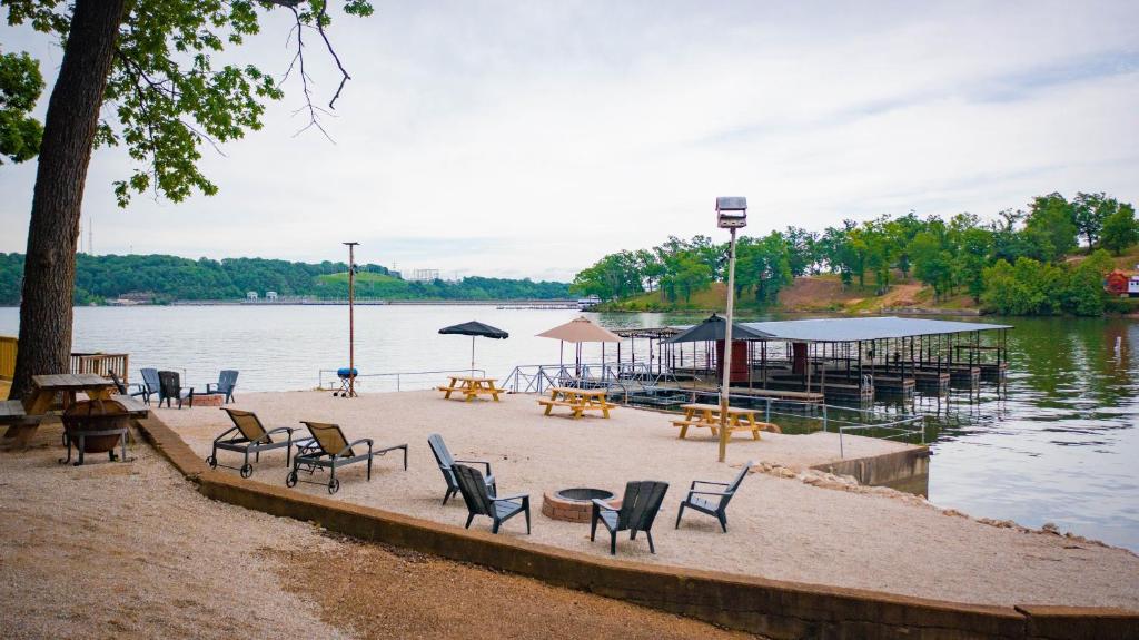 a group of chairs and tables on the shore of a lake at Lakeshore Fishing Cabins All 6 cabins in Lake Ozark
