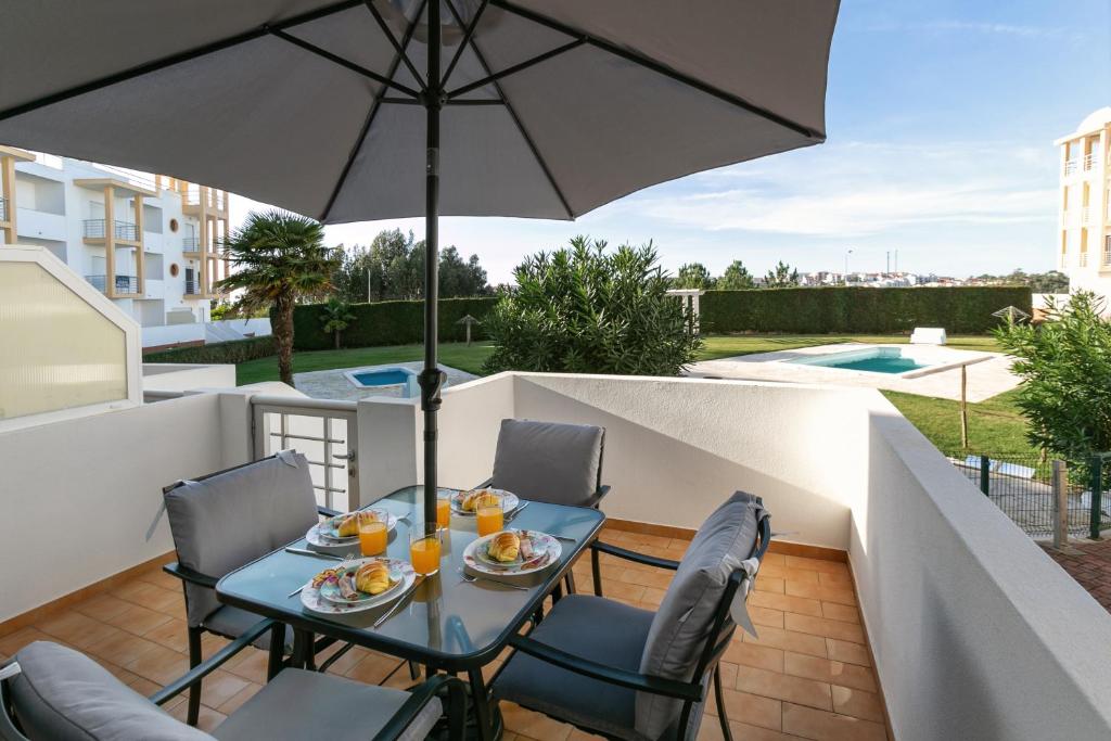 eine Terrasse mit einem Tisch, Stühlen und einem Sonnenschirm in der Unterkunft Paradise Place in Nazaré