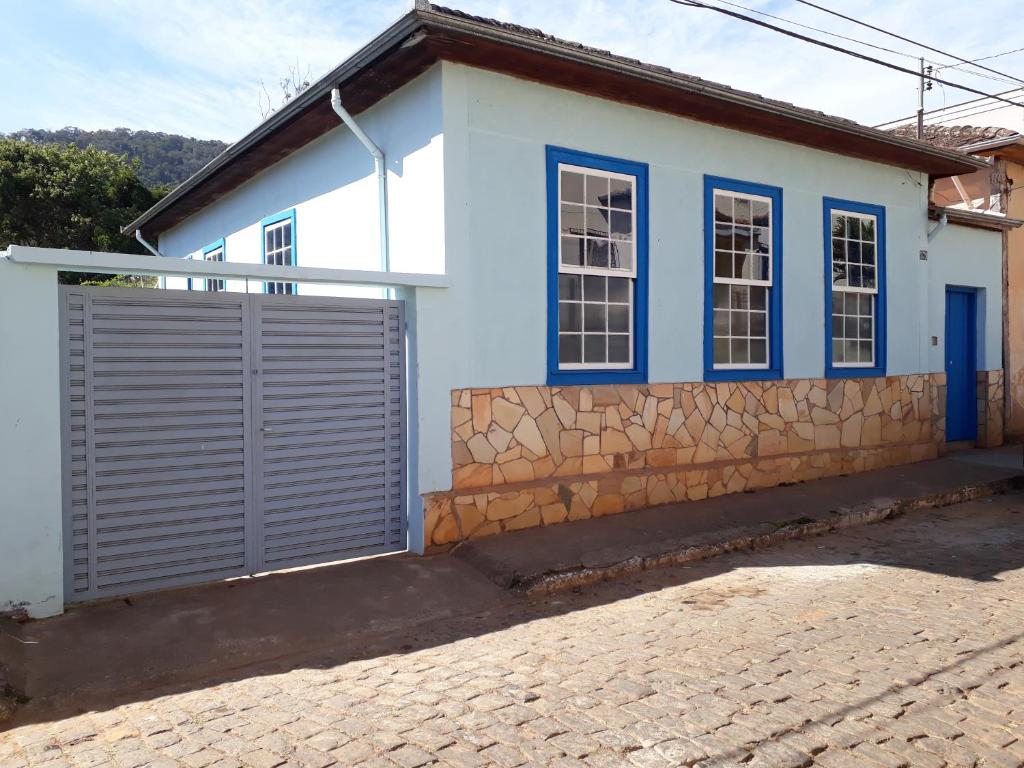 Casa blanca con ventanas azules y valla en Casa estilo colonial, no Centro de Aiuruoca-MG., en Aiuruoca