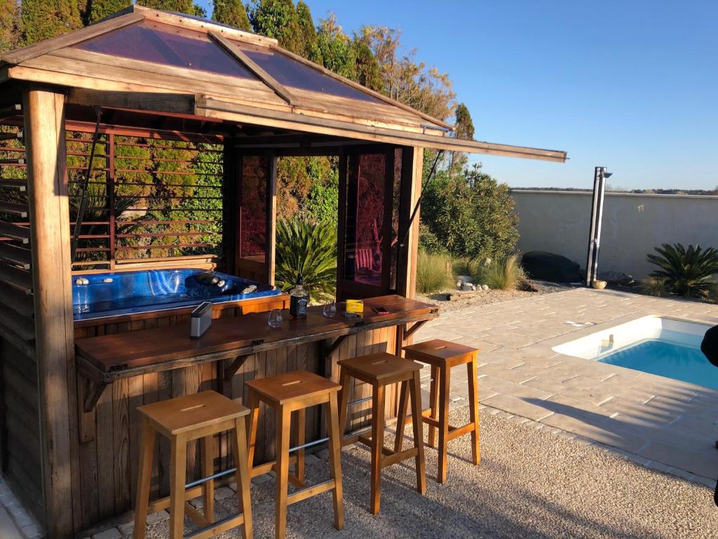 un bar trasero con taburetes y una piscina en Piscine ET JACUZZI ST GEORGES DE DIDONNE a 1km de la plage en Saint-Georges-de-Didonne