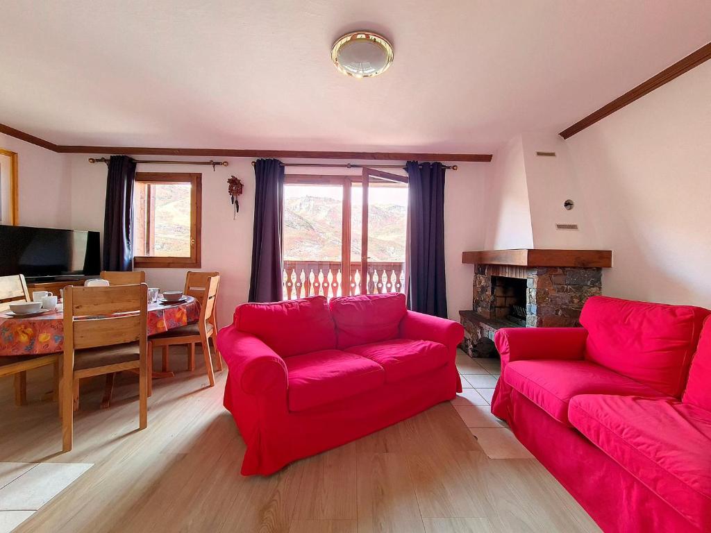 - un salon avec un canapé rouge et une salle à manger dans l'établissement Appartement spacieux Départ ski aux pieds Terrasse - FR-1-344-792, aux Menuires