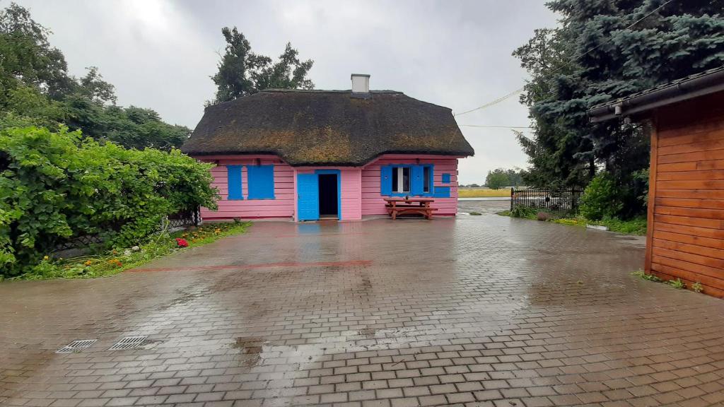 una pequeña casa rosa y azul con techo en Różana Karczma, en Kruszyn