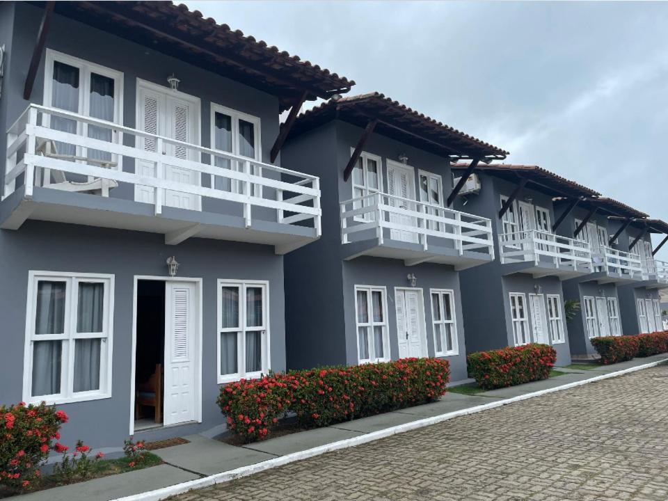ein blaues Gebäude mit weißen Balkonen und roten Blumen in der Unterkunft Apartamento no Taperapuan Duplex in Porto Seguro