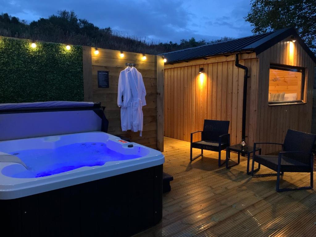 une baignoire installée au-dessus d'une terrasse en bois dans l'établissement River Huts, Highland River Retreat with Hot Tub, à Inverness