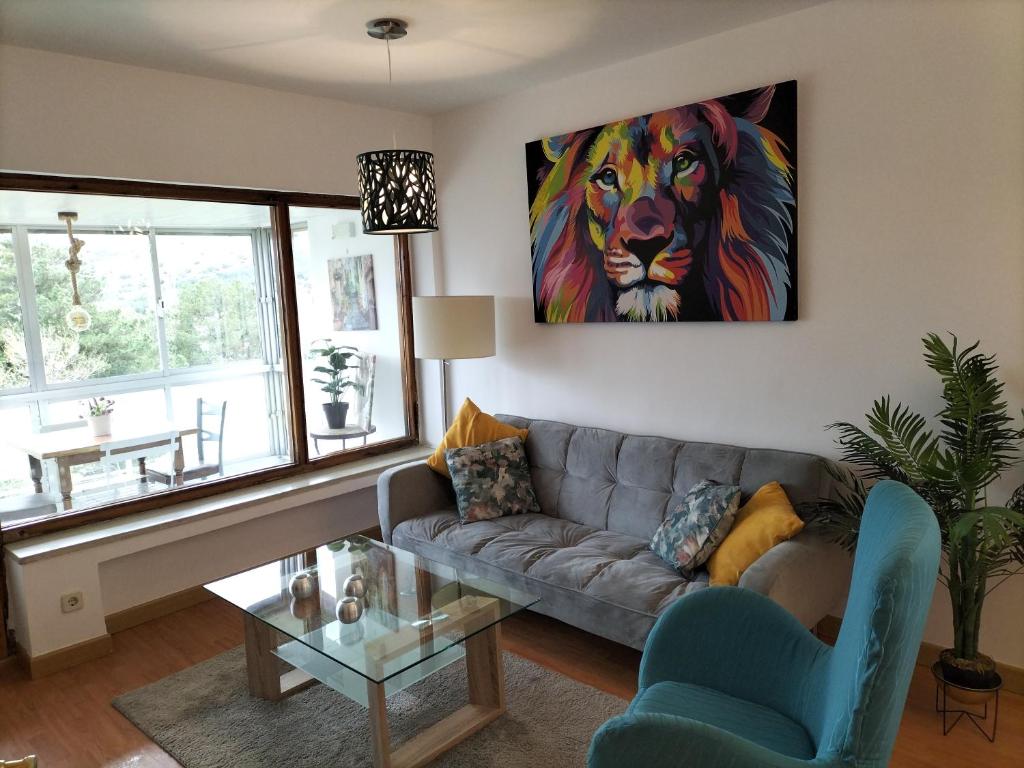 een woonkamer met een bank en een schilderij van een leeuw bij El Coqueto de Segovia in El Espinar