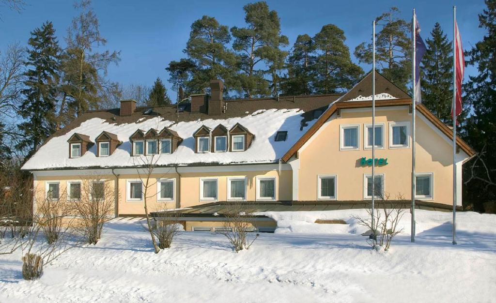 une grande maison jaune avec de la neige sur son toit dans l'établissement Austria Classic Hotel Hölle, à Salzbourg