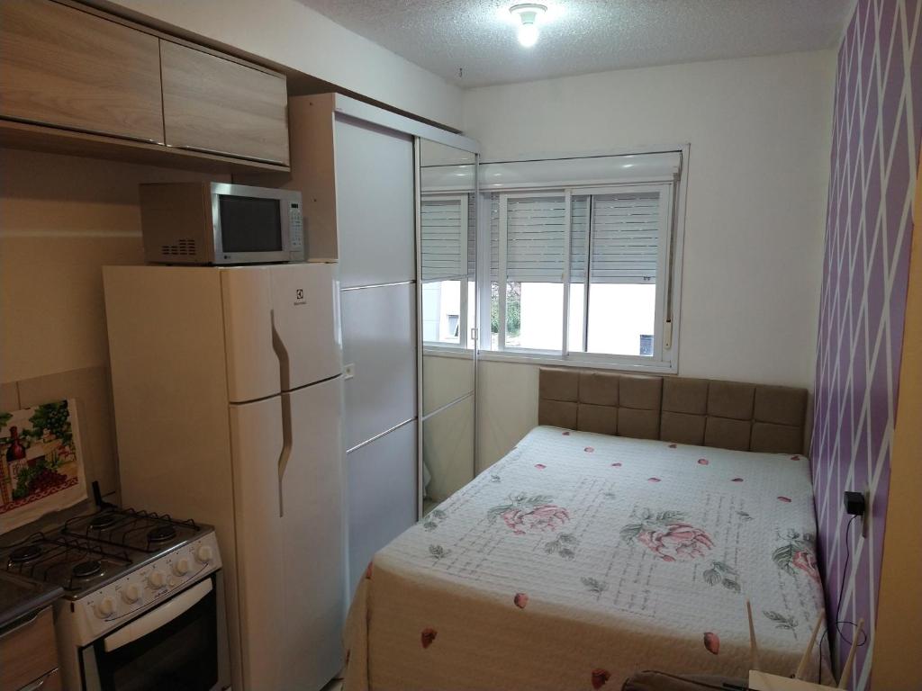 a small kitchen with a bed and a refrigerator at Apartamento Aconchego in Bento Gonçalves