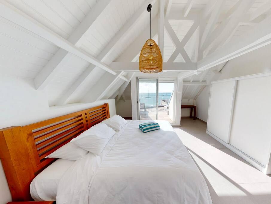 Un dormitorio con una gran cama blanca y una ventana en Walee Beach Penthouse by the sea, 2 bedrooms, pool, en Saint Martin