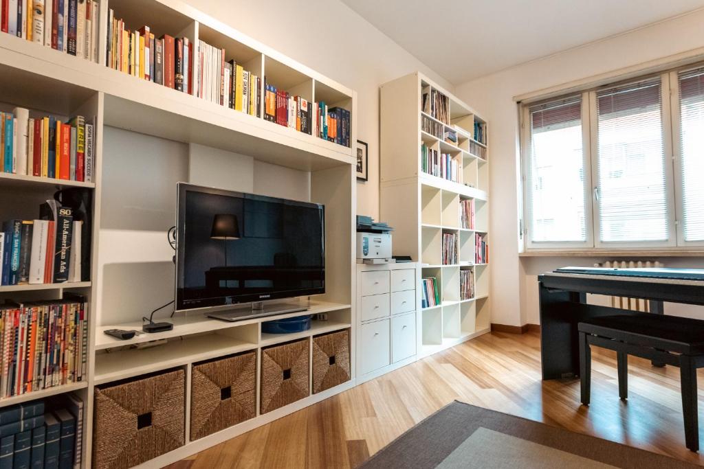 a living room with a tv and book shelves at Sebino Guest House in Milan