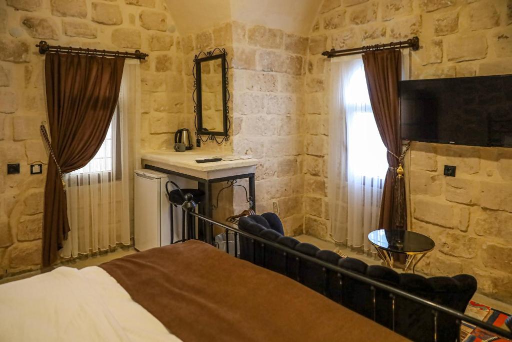 ein Schlafzimmer mit einem Bett und einer Steinmauer in der Unterkunft Nostalji in Mardin