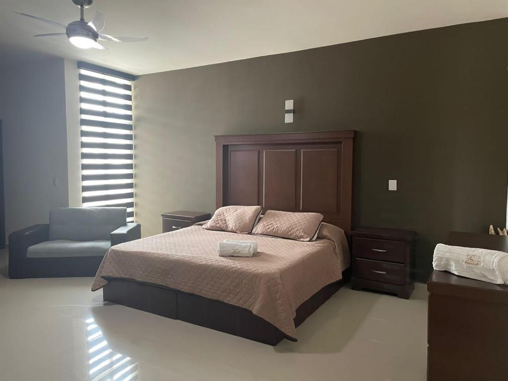 ein Schlafzimmer mit einem Bett, einem Stuhl und einem Fenster in der Unterkunft Suite Hotel San Salvador in San Juan de los Lagos