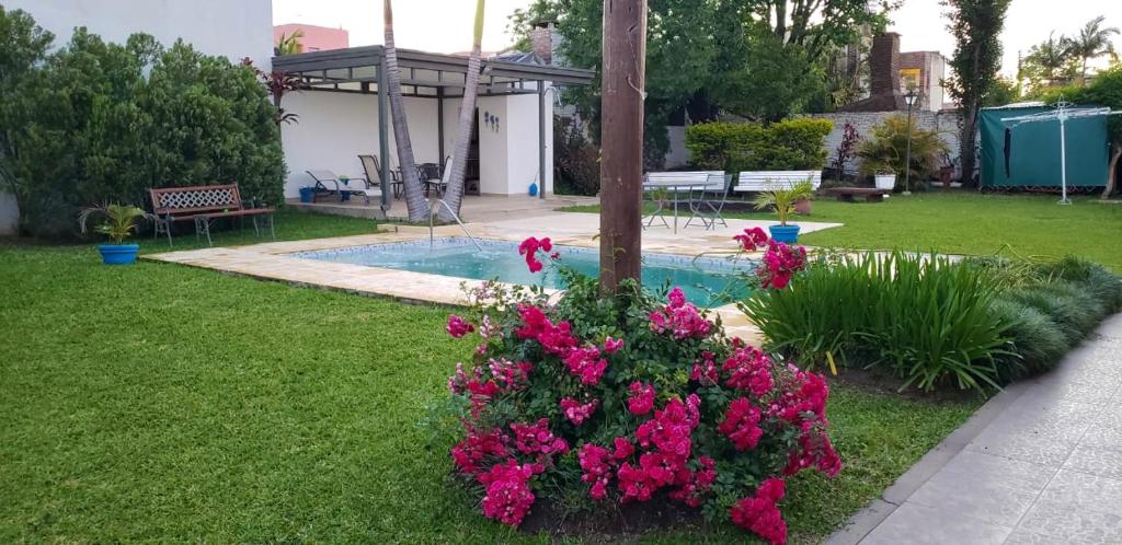 un jardín con flores rosas y una piscina en La Alamanda en Federación