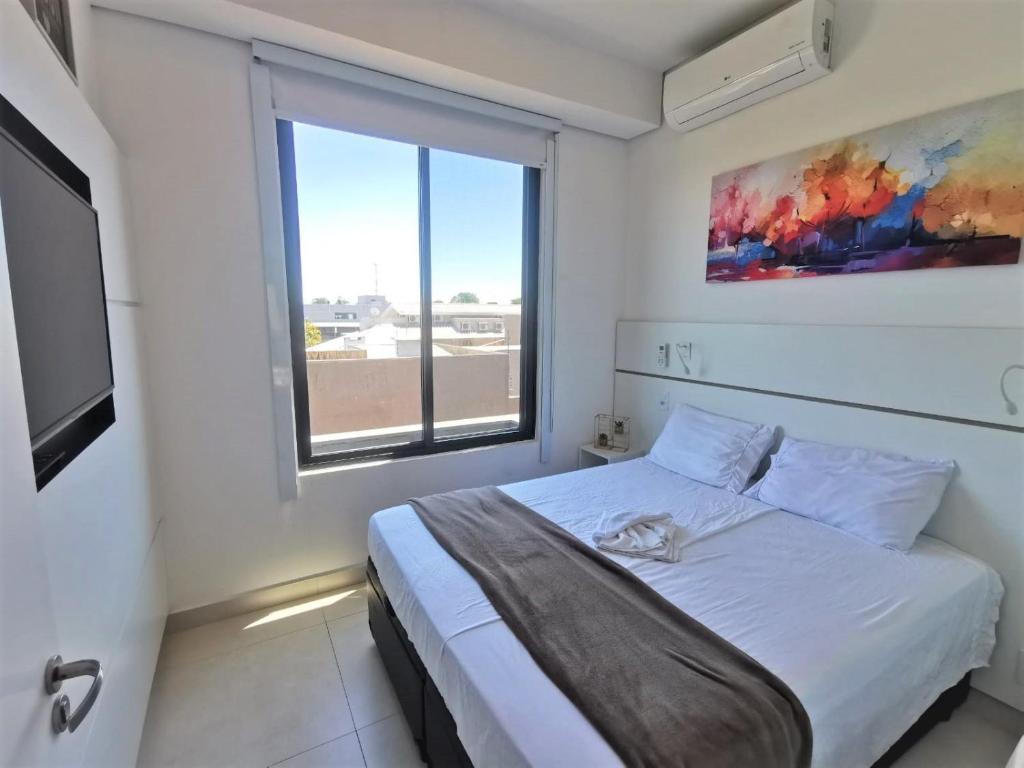um quarto com uma cama e uma grande janela em Click Apê Cataratas Luxo em Foz do Iguaçu