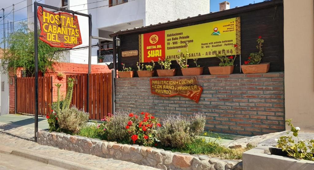 een gebouw met planten en een bord erop bij Hostal del Suri in Cafayate