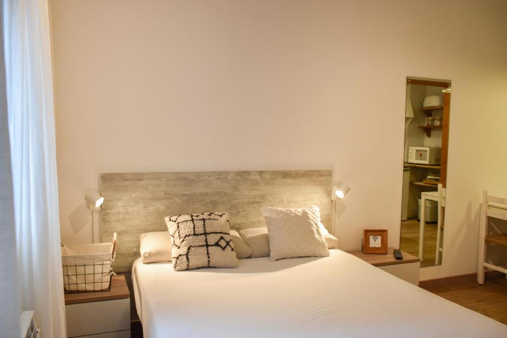 um quarto com uma cama com lençóis brancos e almofadas em ESTUDIO AVET - Perfecta ubicación em Pas de la Casa