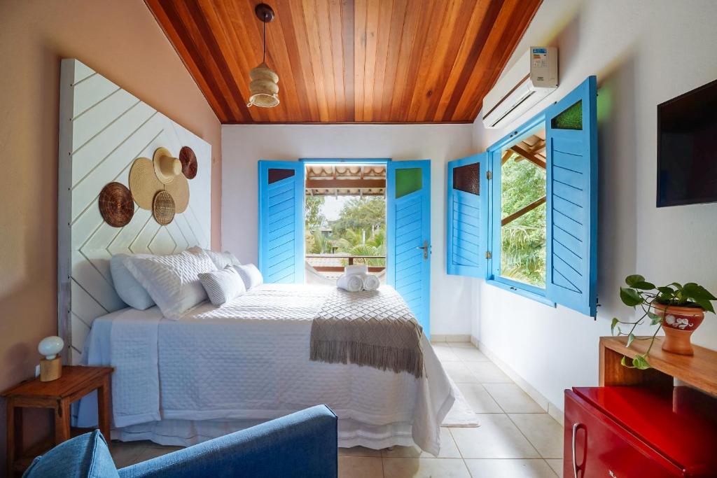 Pousada Sabina في بارا غراندي: غرفة نوم بنوافذ مغلقه زرقاء وسرير
