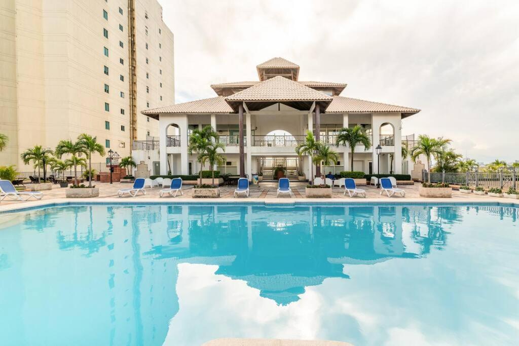 a large swimming pool with chairs and a building at Luxurious 2BDR condo located in Prestigious Tower. in Santo Domingo