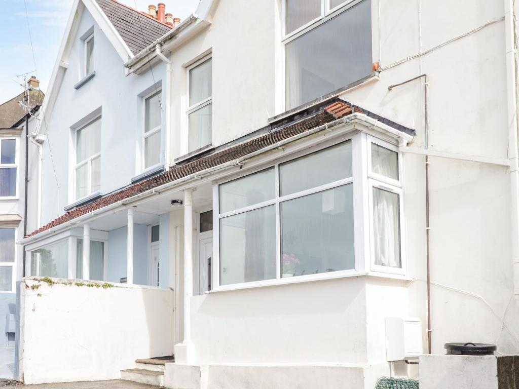 a white house with large windows at Gwylan Apartment in Tenby