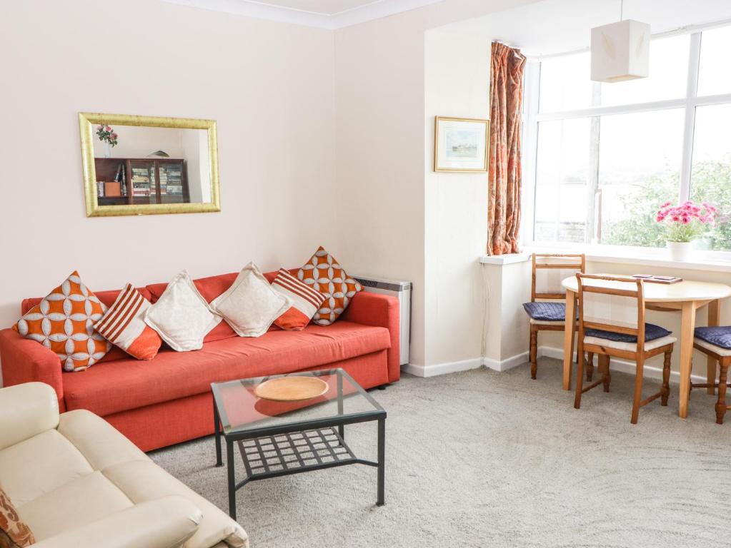a living room with a red couch and a table at Gwylan Apartment in Tenby