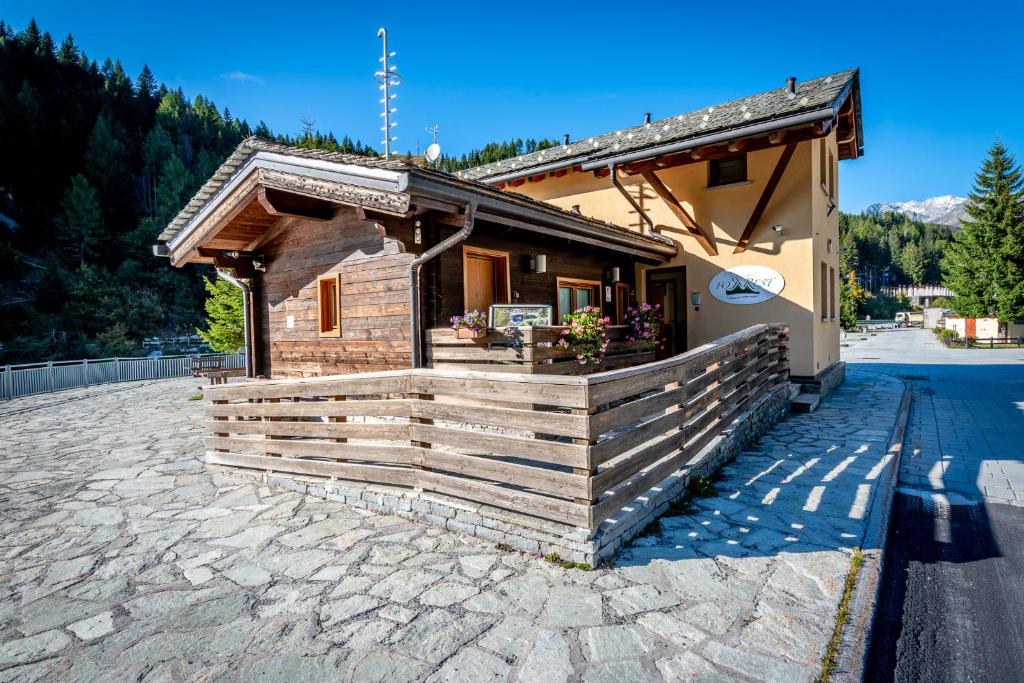 een klein houten gebouw met een veranda op een stenen patio bij For Rest in Madesimo