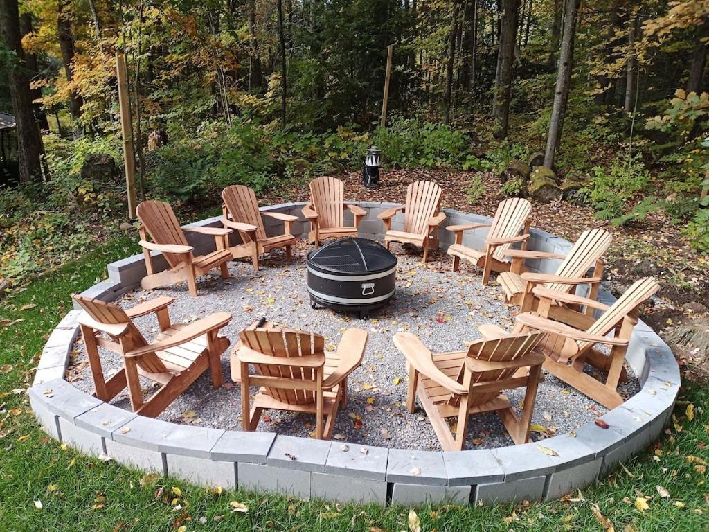 einem Kreis von Stühlen und einer Feuerstelle mit einem Grill in der Unterkunft Fireside - Waterfront Resort Style Executive Cottage in Kawartha Lakes