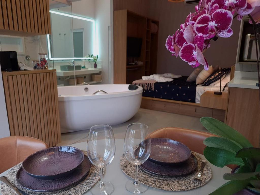 a table with wine glasses and a bathroom with a tub at Esquina Brotense_Hospedagem de charme in Brotas