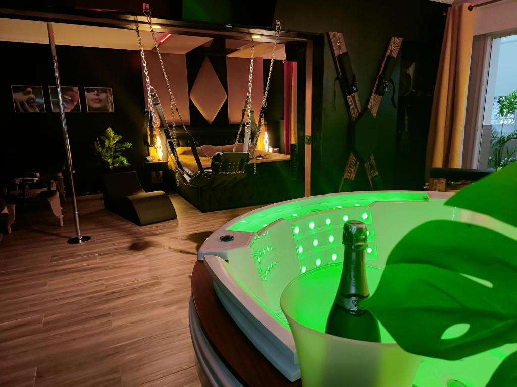 - une table verte avec une bouteille de champagne dans l'établissement La loveroom bdsm de Nice " la chambre luxe des désirs ", à Nice
