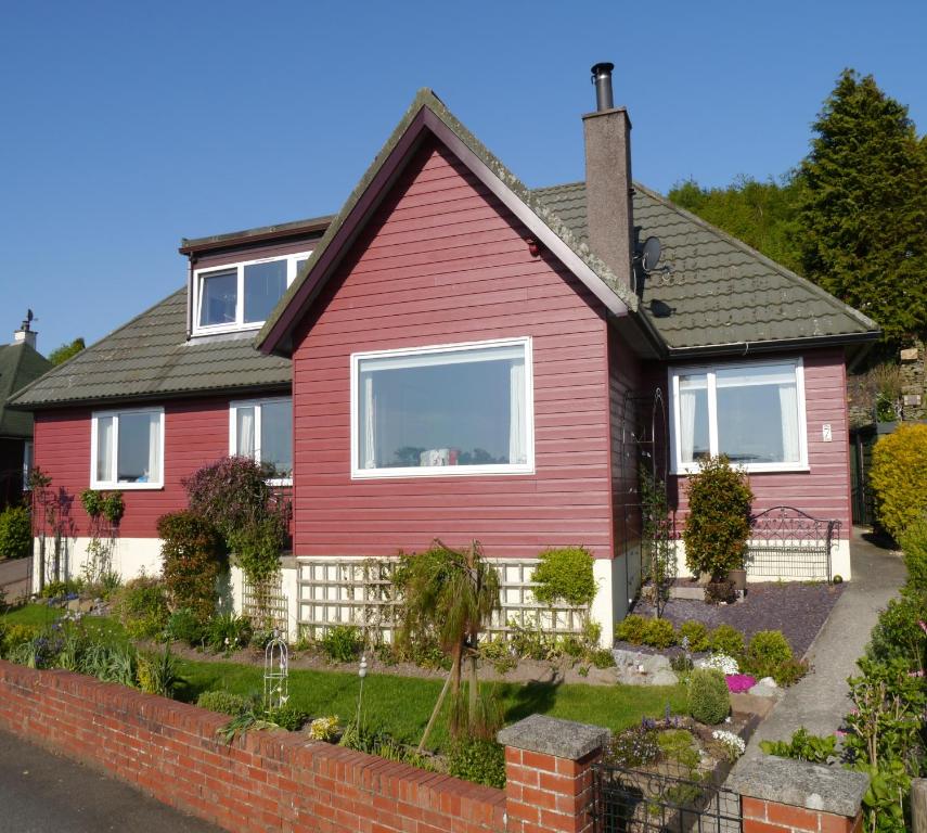 a red house with a garden in front of it at Arakhova in Kirkcudbright