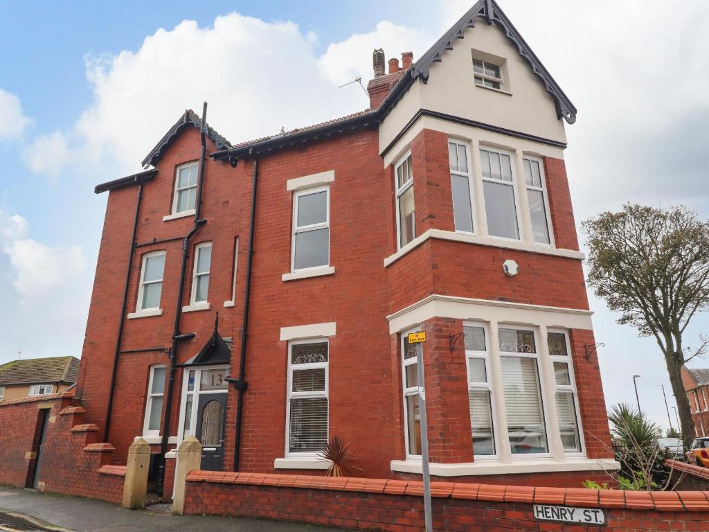 a red brick house with white windows on a street at Yewdale in Lytham St Annes